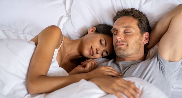 man and woman cuddle in bed